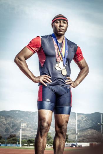 A photo of Tyree Washington posing with medals in track attire