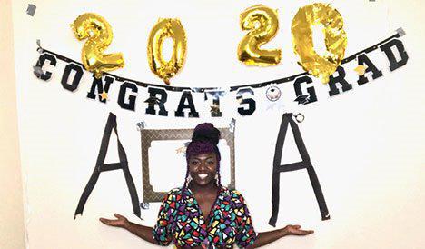 A photo of Narishia Laye in front of a "2020 Congrats Grad" sign.