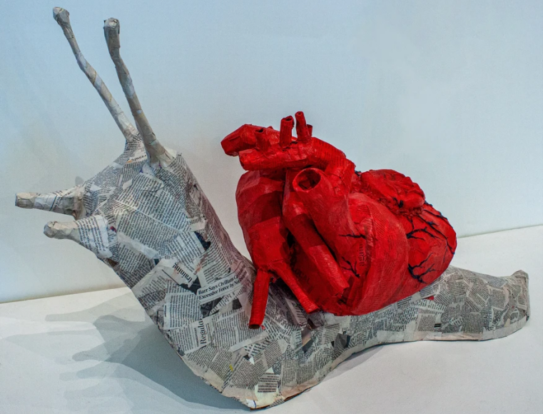 A snail made of paper mache with a anatomical heart for a shell