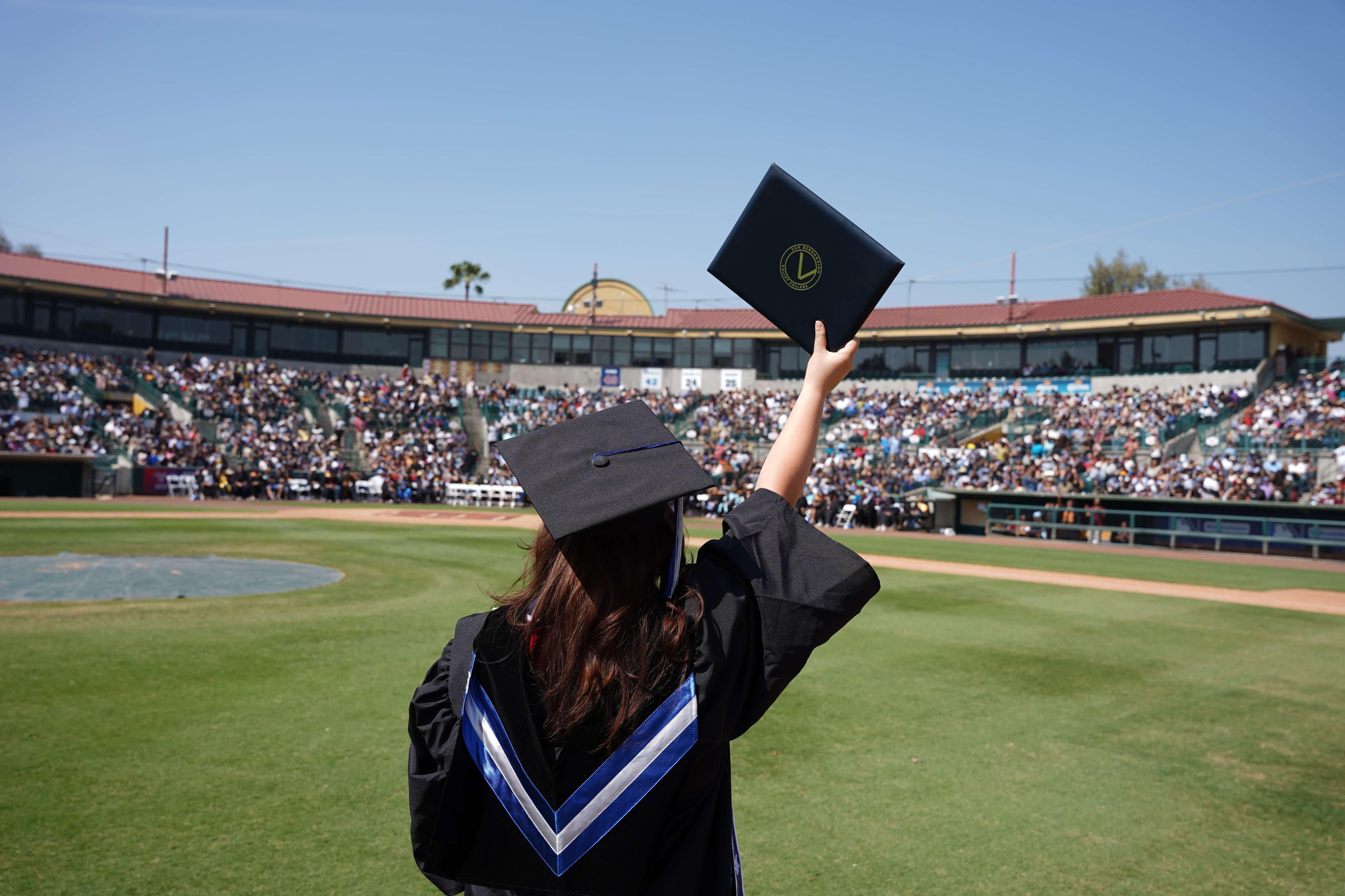 Two graduates smile and pose as they walk to their seats