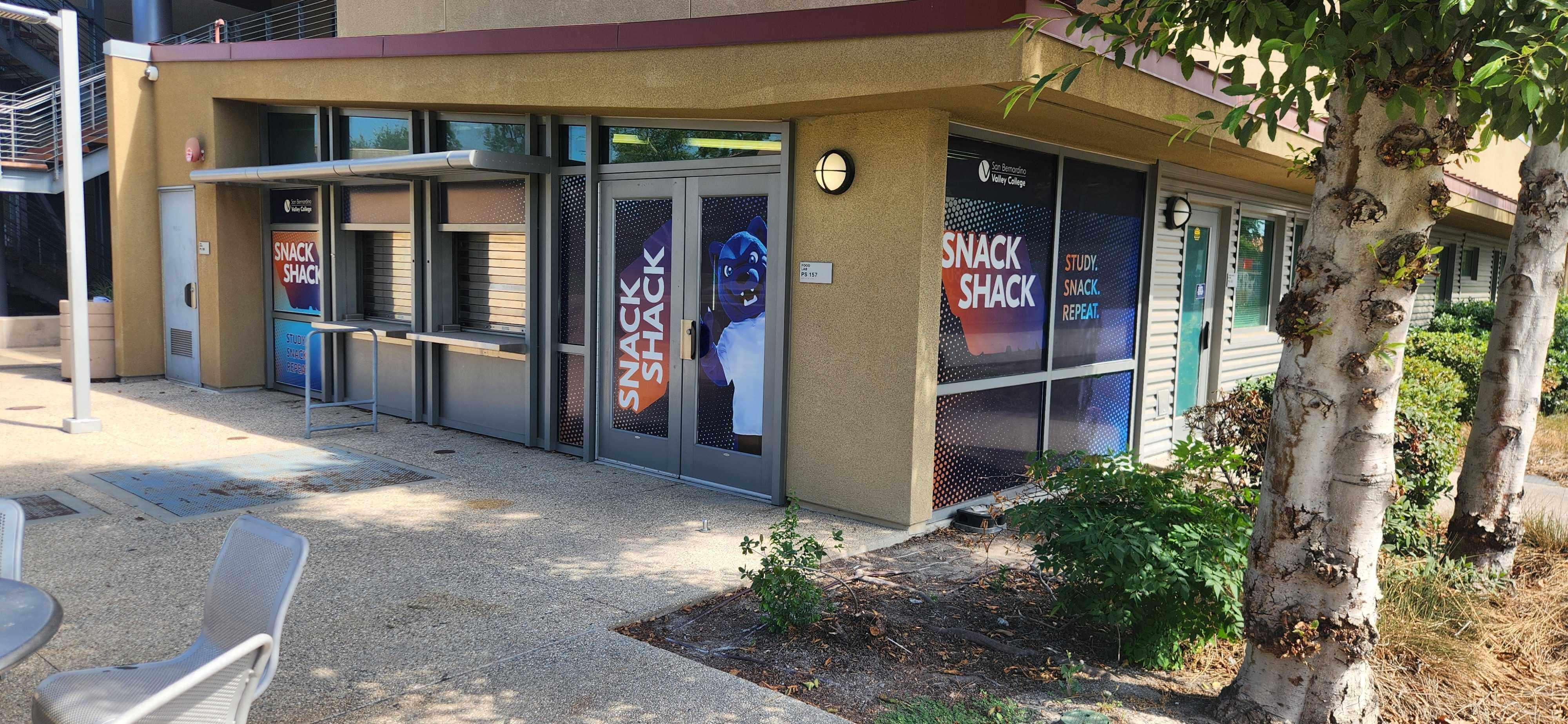Exterior of the SBVC Snack Shack, featuring service windows, branded window graphics, and the college’s Blue mascot near the entrance.