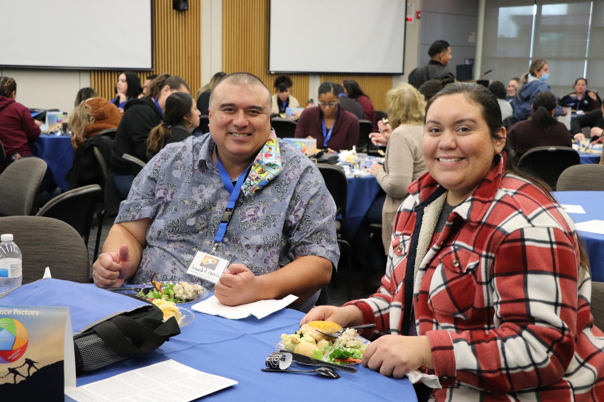 A photo of two counselors smiling while eating lunch