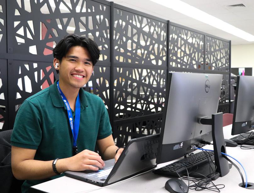 A student working on a laptop looking up and smiling