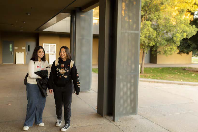 two students standing in a hallway smiling on campus