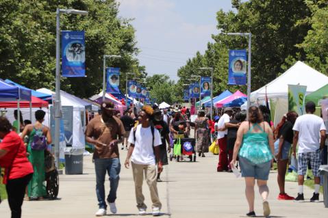 Students walking down SBVC campus center walk with vendors on either side.
