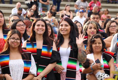 Graduates of the Nuestra Grad waving and smiling at the camera