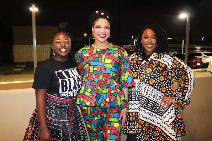 Three women standing in a row smiling for the BHM Fashion Show