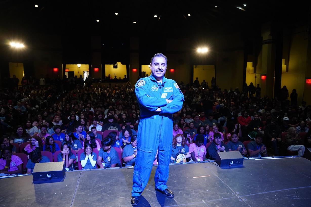 Jose Hernandez poses with his back to a crowd of students in the SBVC Auditorium