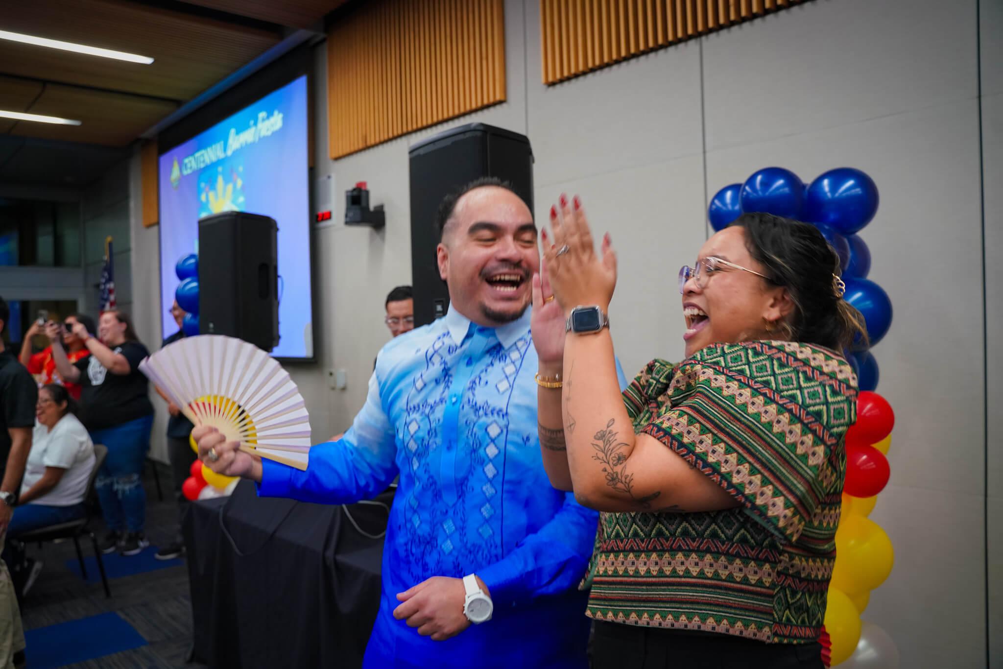 Rangel Zarate holding a paper fan and smiling with Marie Maghuyop