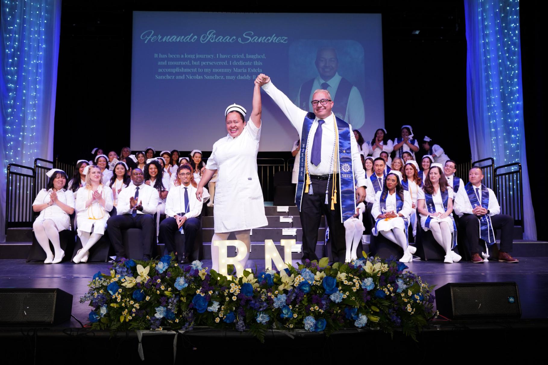 A nurse and graduate holding hands and raising them in excitement
