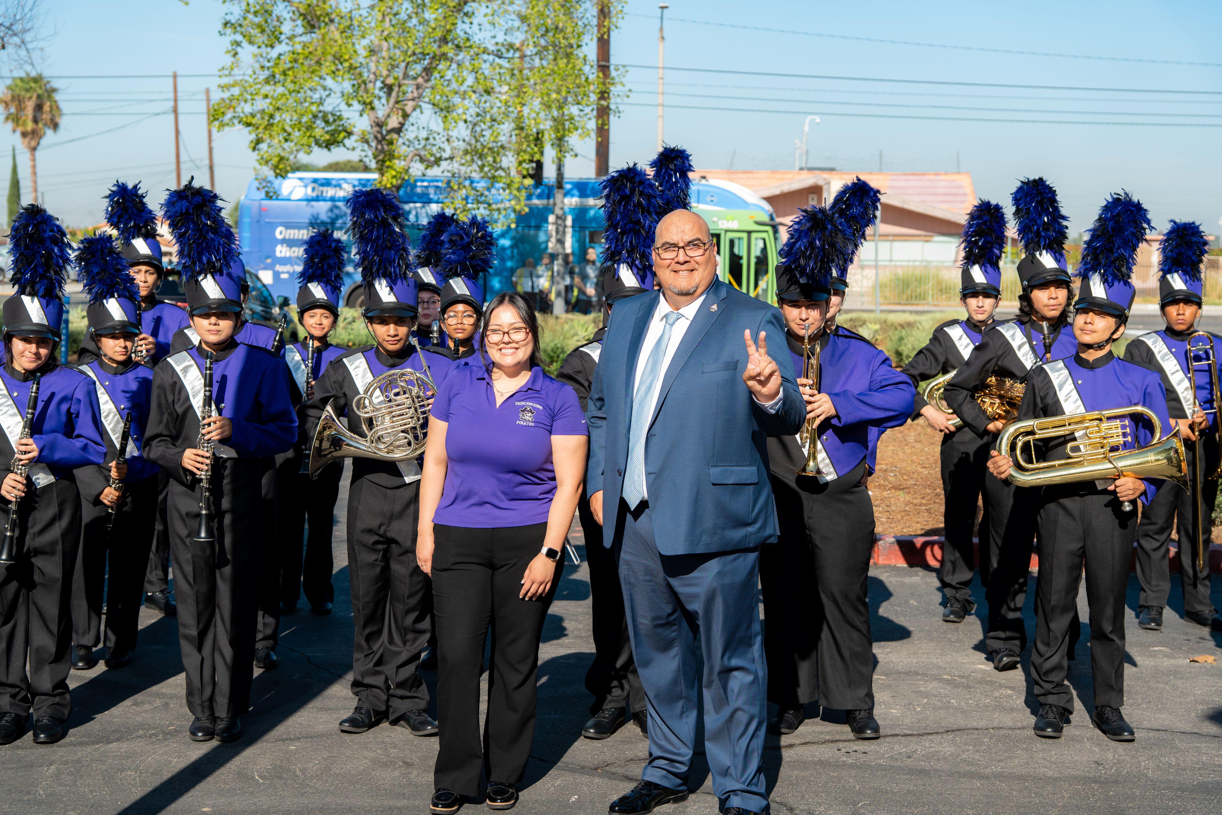 SBVC president poses with the Pacific High School marching band making the V sign with his hand