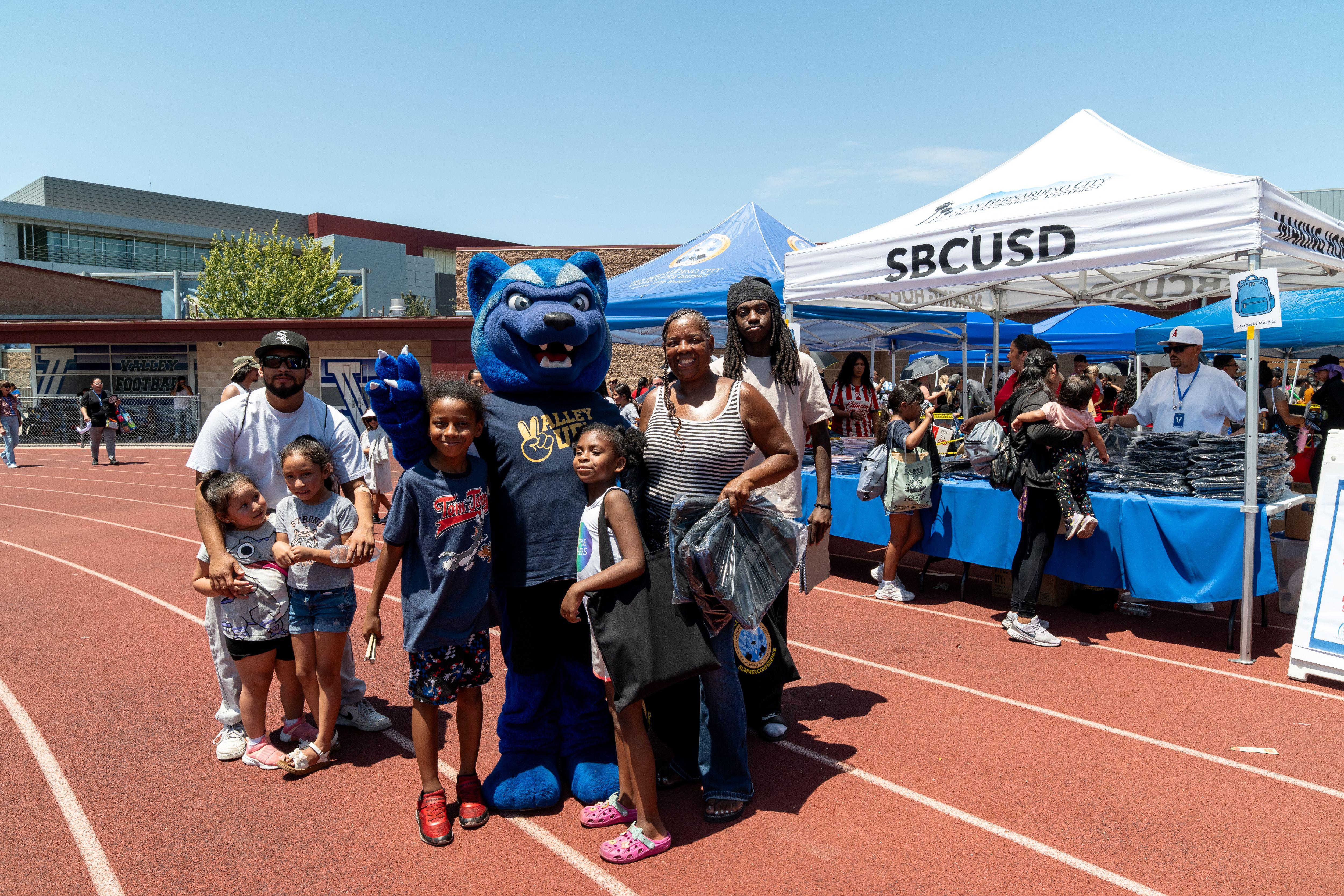 Adults and children stand with SBVC mascot Blue