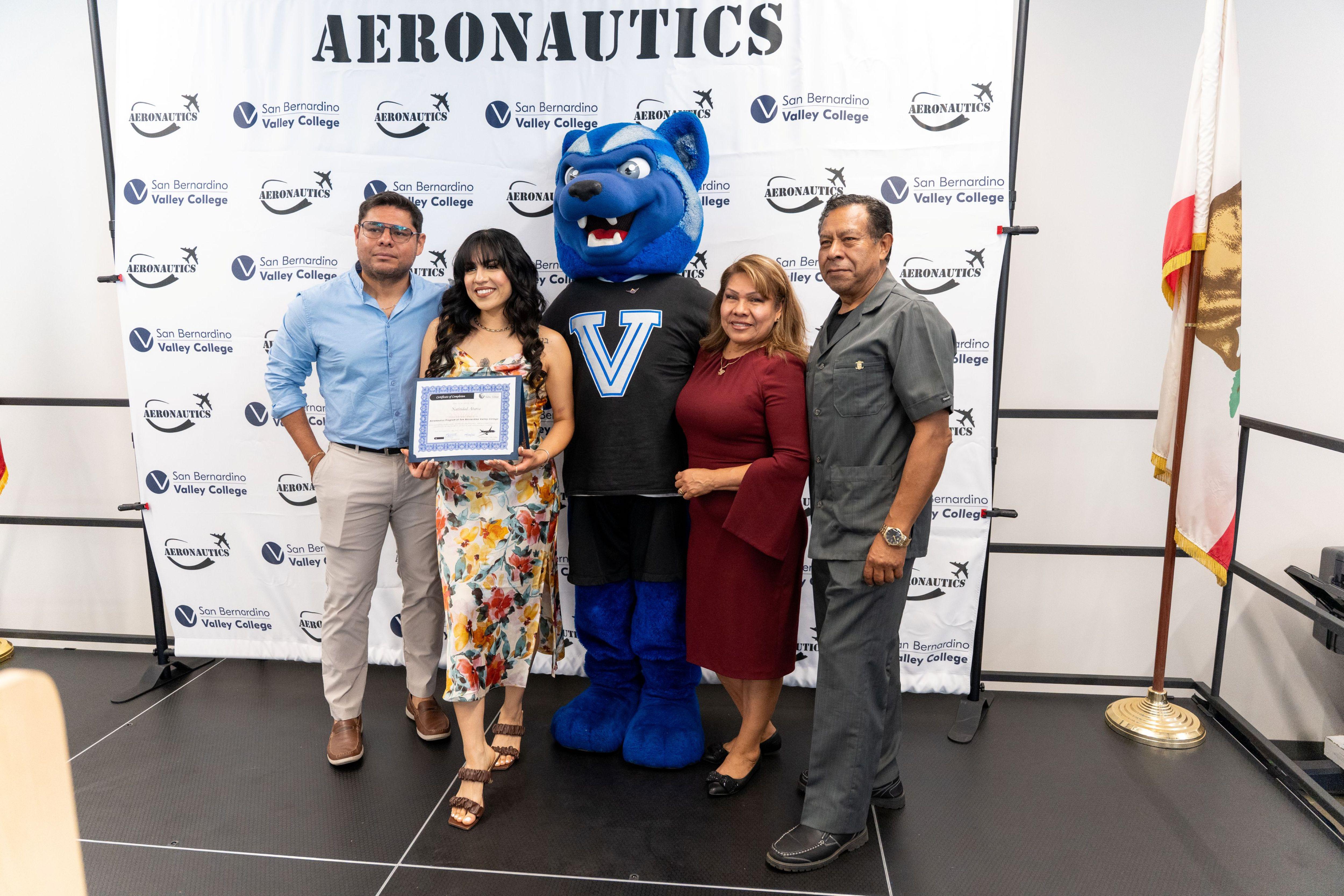 graduate poses with her family and SBVC mascot Blue