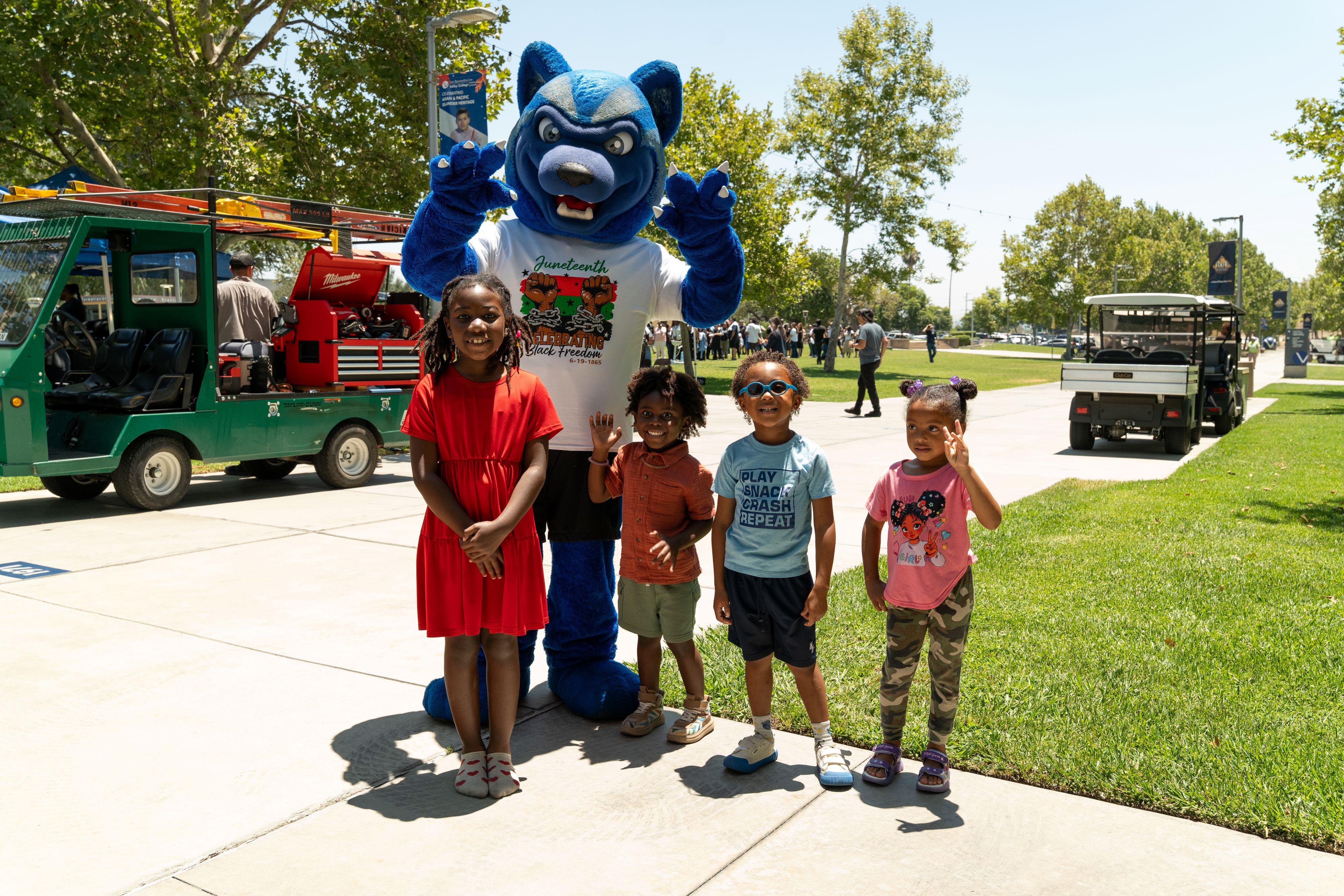 Four children pose with SBVC mascot Blue