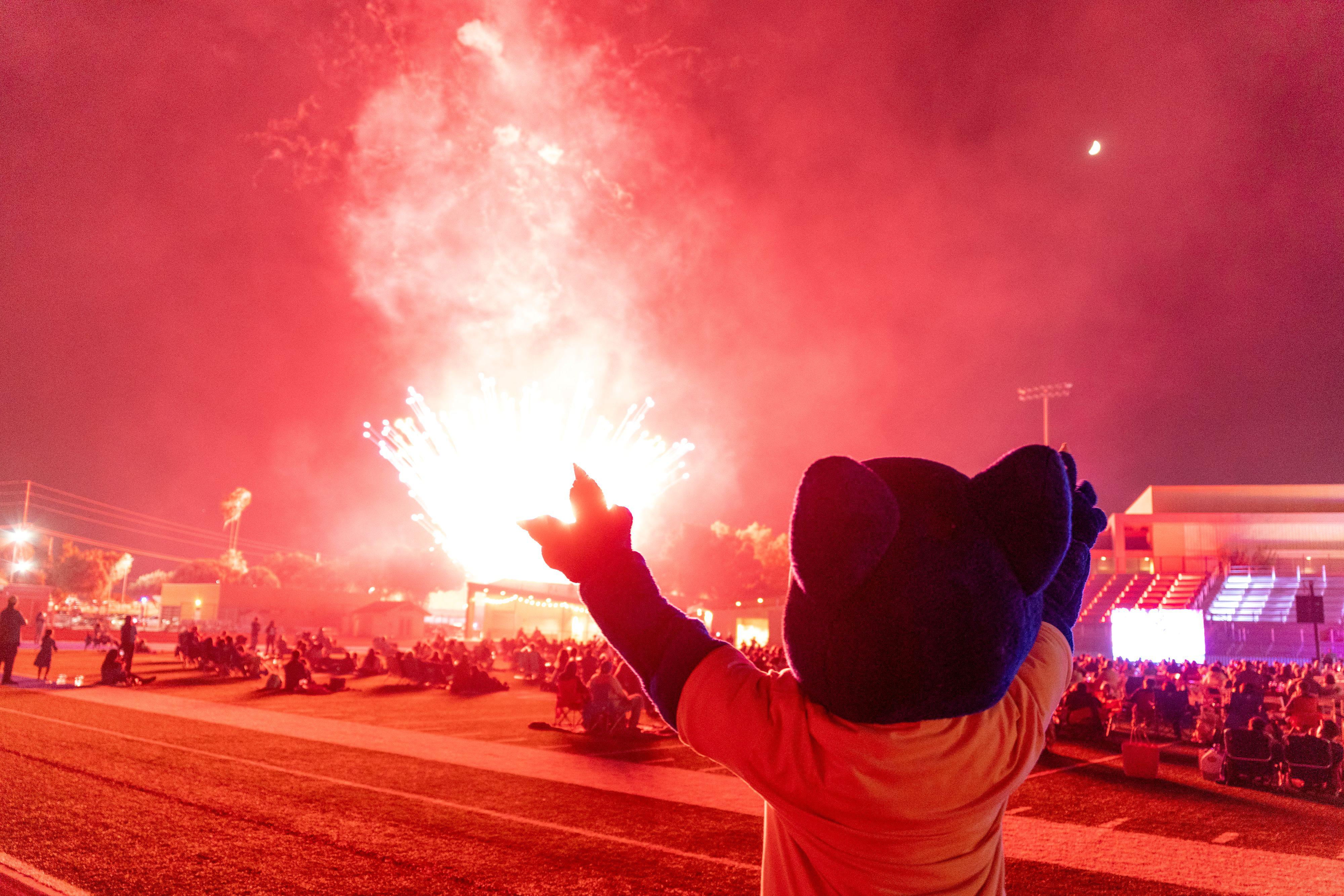 Fireworks are shot off with SBVC mascot Blue raising his arms in the foreground