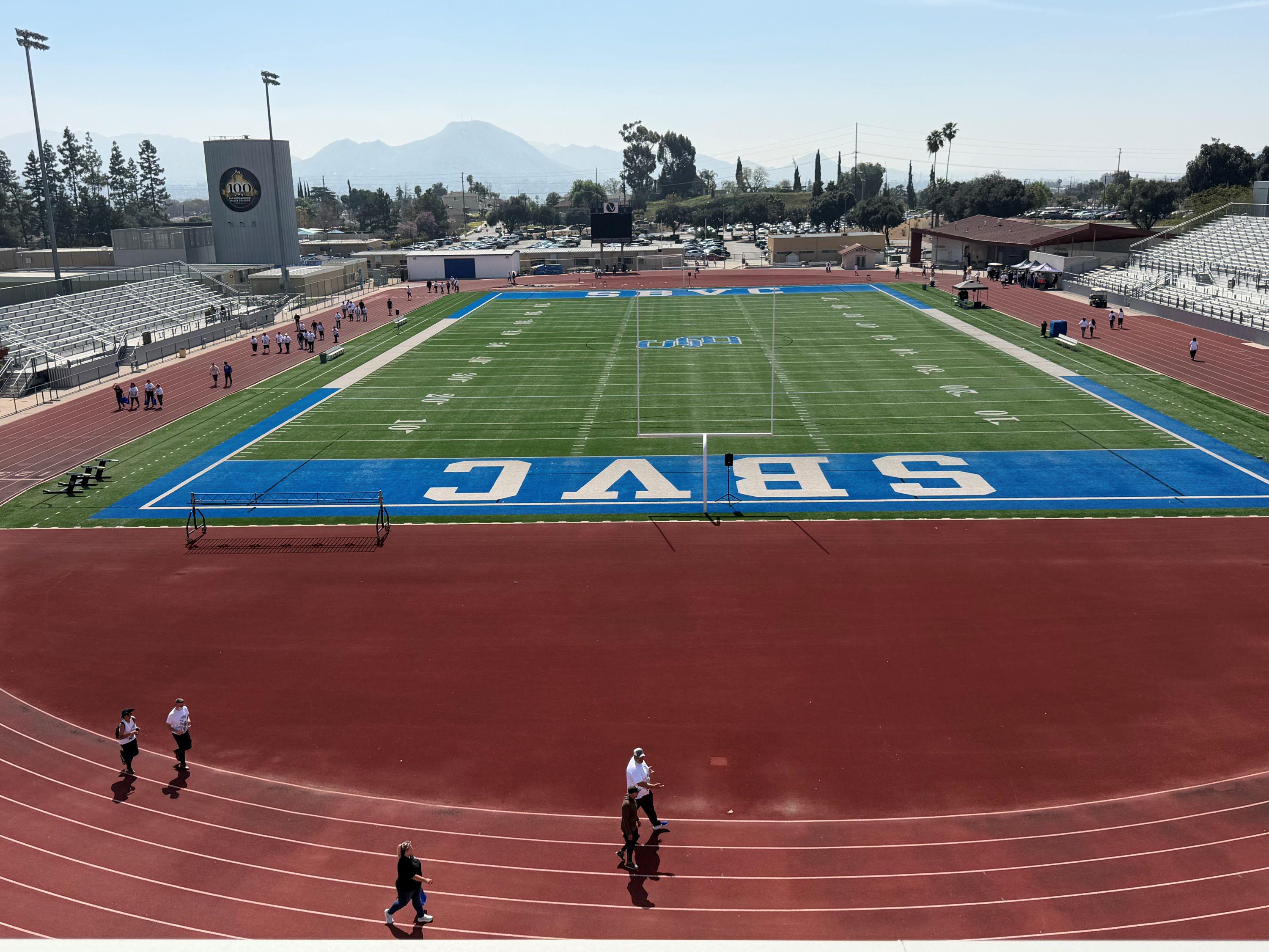 People walk around a track at a college stadium