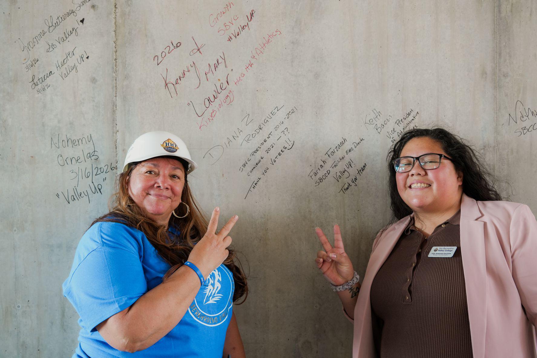 Two women in front of a signed wall at a construction site