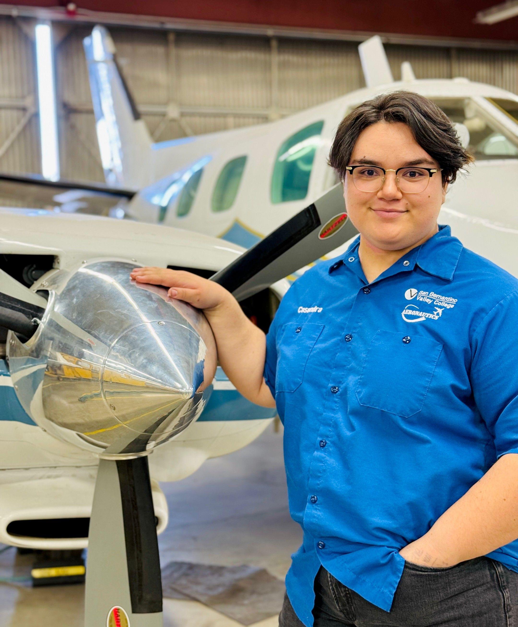Woman stands with her hand on an airplane propeller