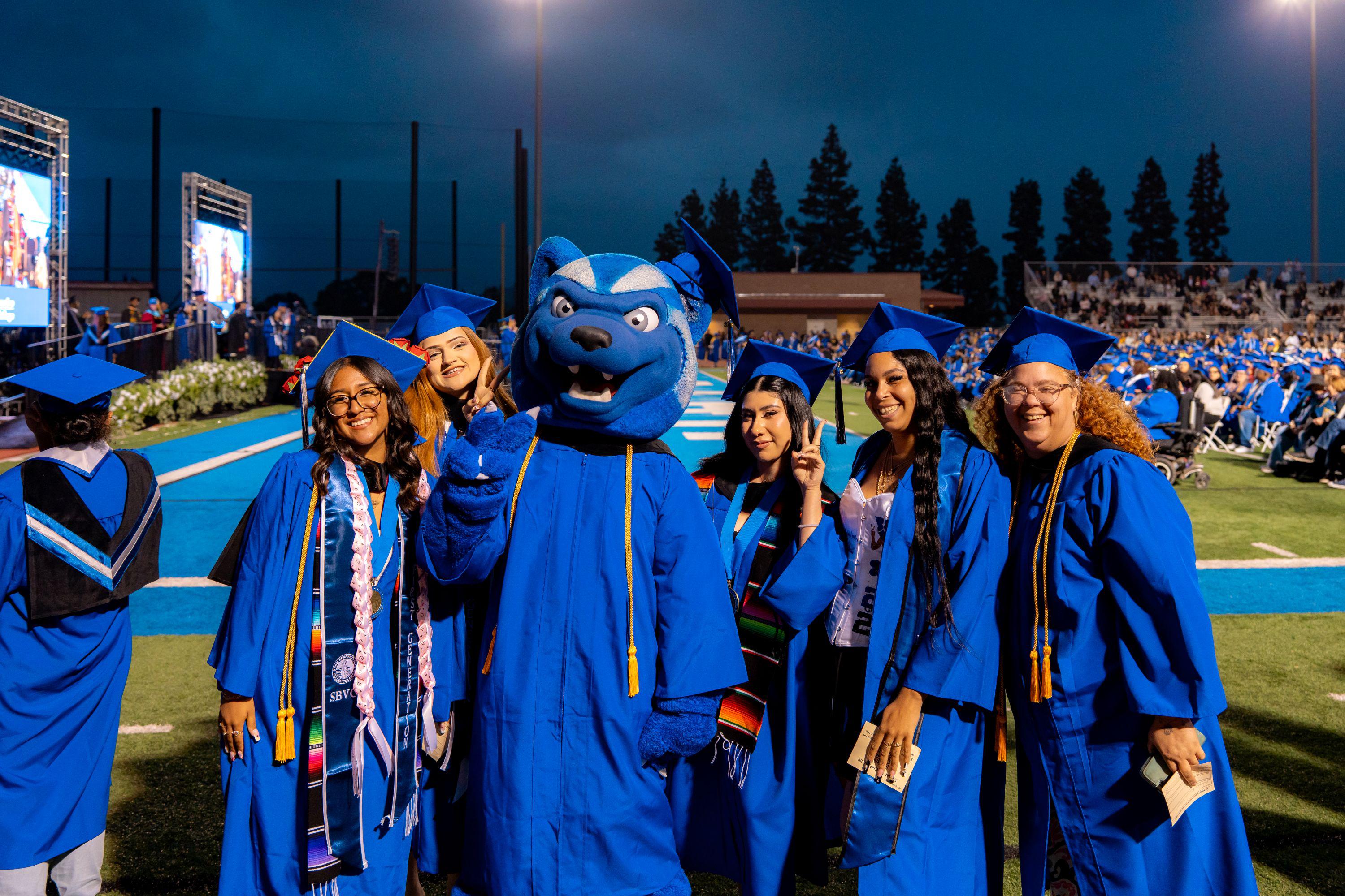 Female graduates pose with mascot Blue
