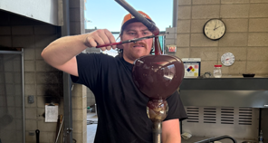 Man holds a tool to molten glass