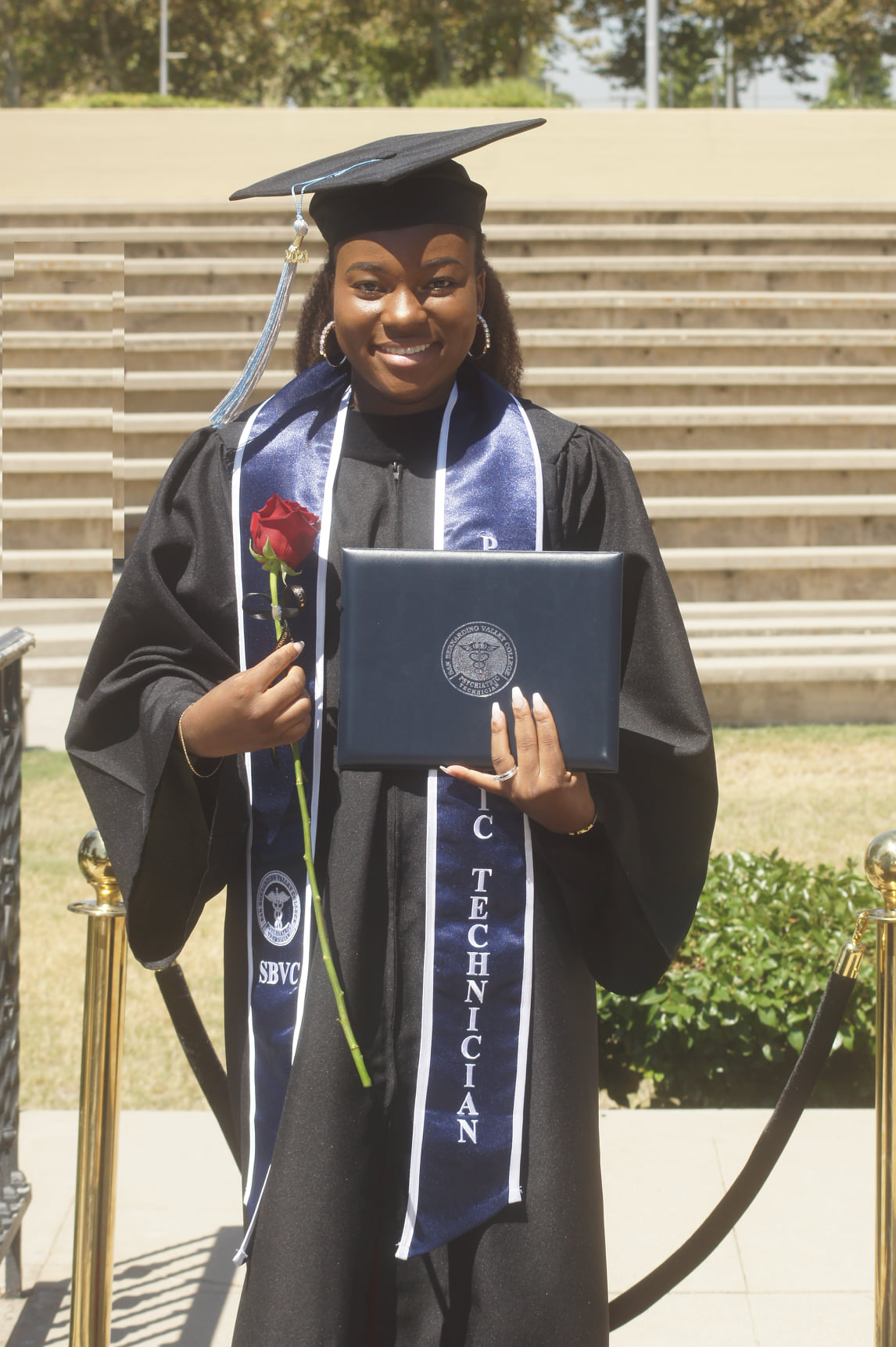 A Psych Tech grad in a cap in gown smiles