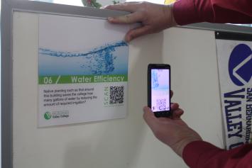 picture of person using smartphone to scan QR code on LEED sign