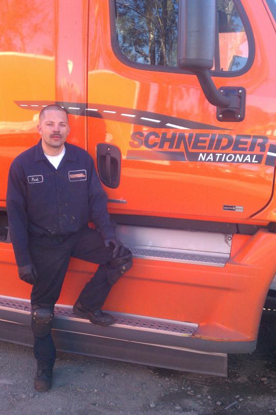 student paul prado poses next to an orange schneider semi-truck